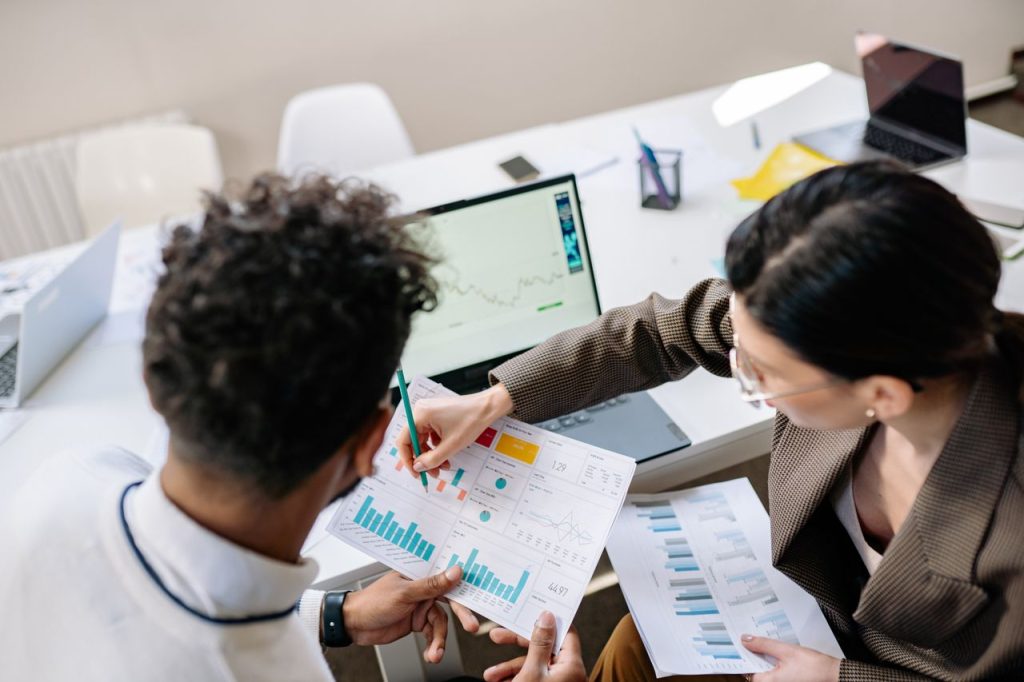 Top 10 SEO Strategies to Rank Higher on Google Two colleagues in a meeting room discussing financial charts and graphs on a laptop and paper.